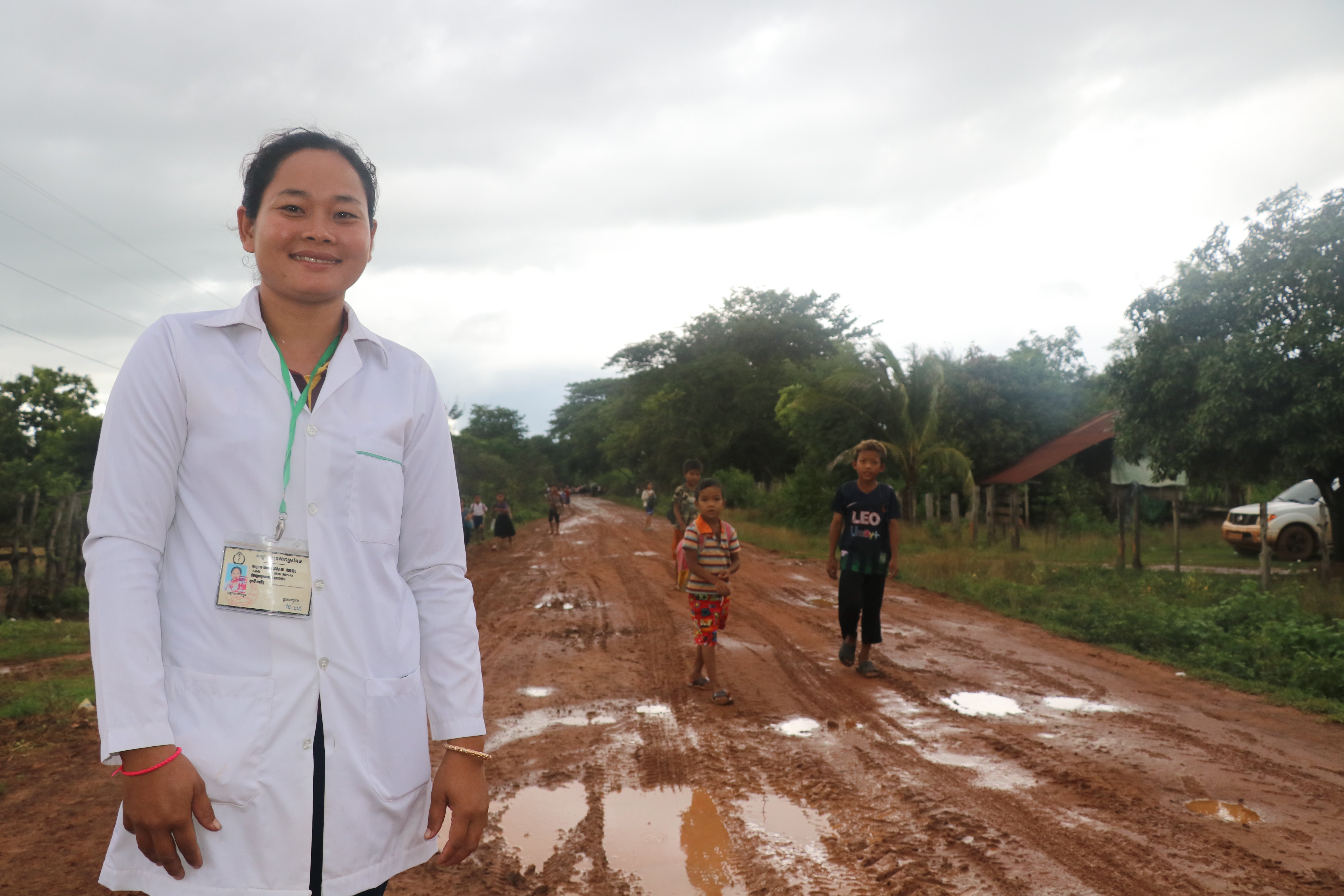 Ratana stands in a dirt-road from the health post to village